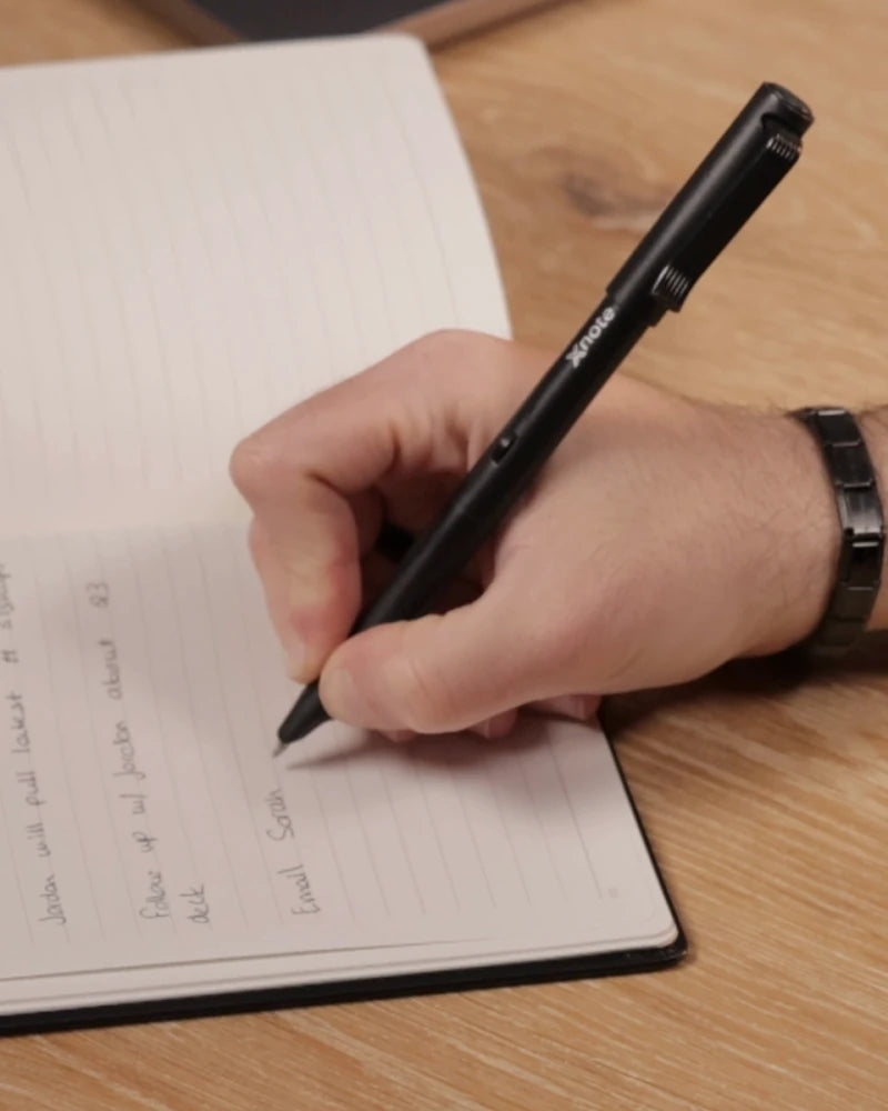 A hand writing with the XNote pen in an XNote notebook