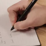 Writing with the XNote smart pen in an open XNote Standard notebook (Standard notebook shown)