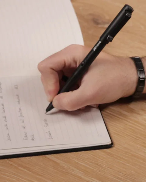 Writing with the XNote smart pen in an open XNote Standard notebook (Standard notebook shown)